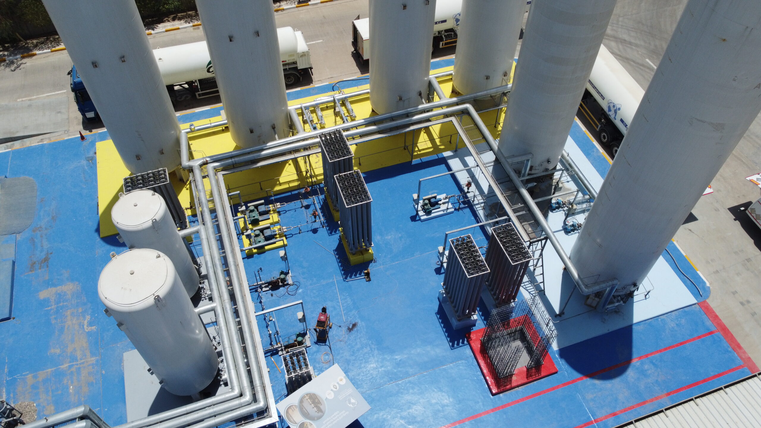 Aerial view of Alaalamiya industrial gas plant showing the central zone between massive storage tanks with visible equipment and infrastructure